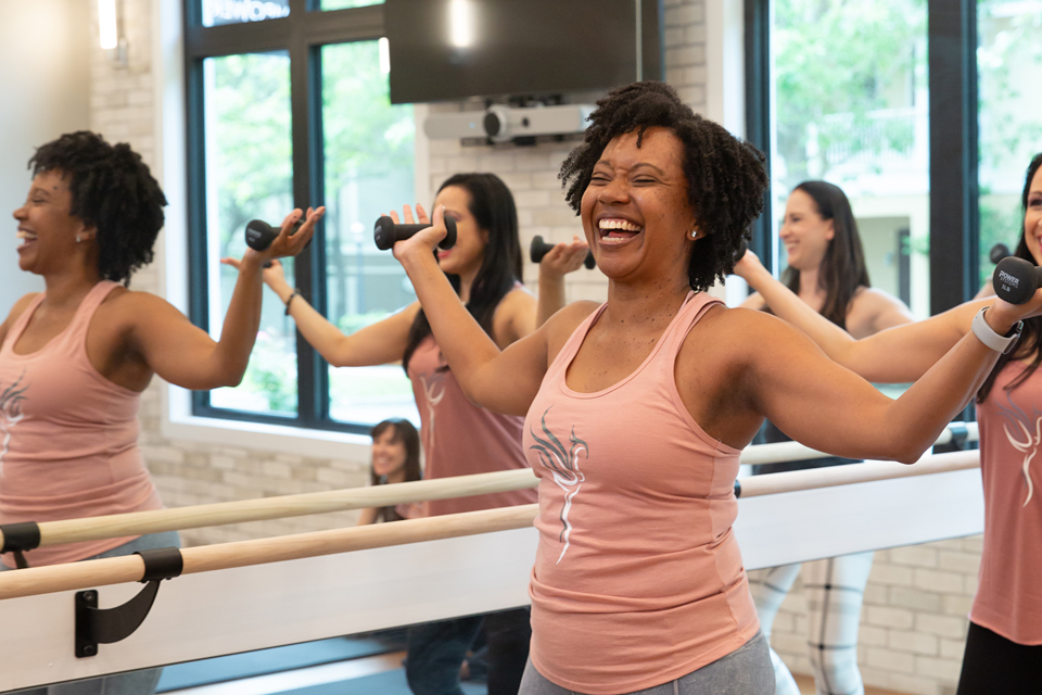 image of a woman smiling at a barre class