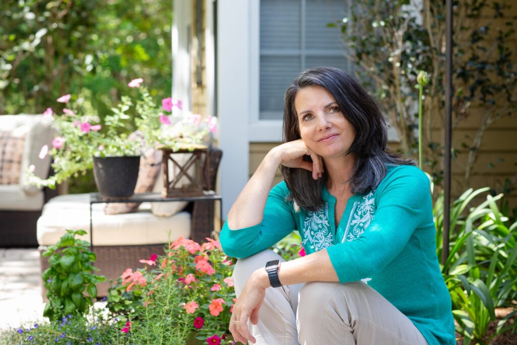 portrait of an author sitting on her back steps, resting her elbow on her knee and looking at the camera